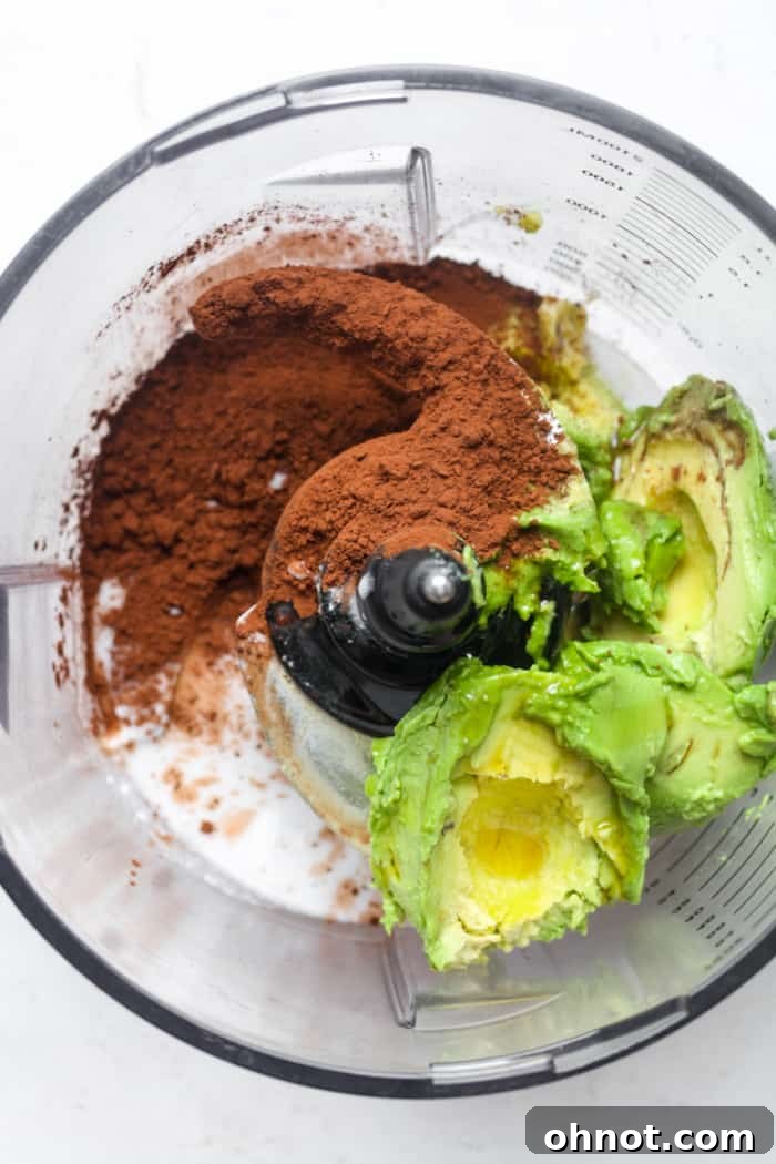 Cocoa powder being added to a food processor with other ingredients.