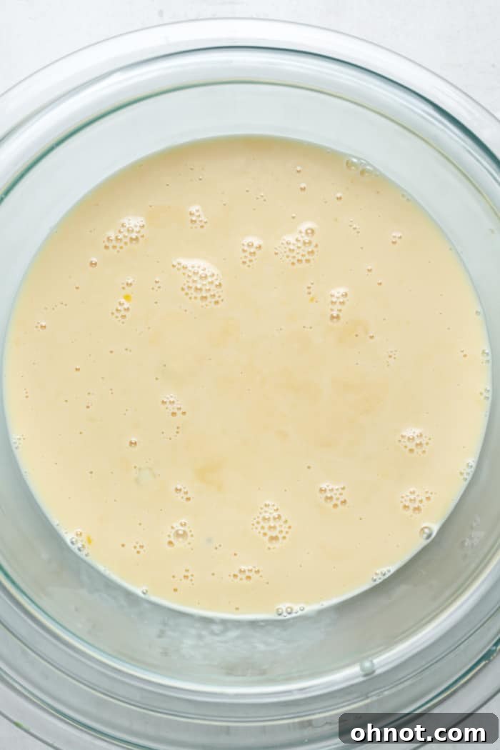 Warm custard mixture being poured into a bowl set in an ice bath.
