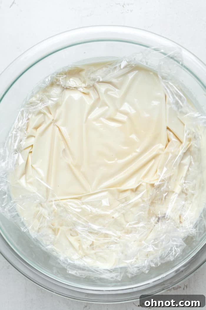Bowl of ice cream custard covered with plastic wrap, ready for chilling.
