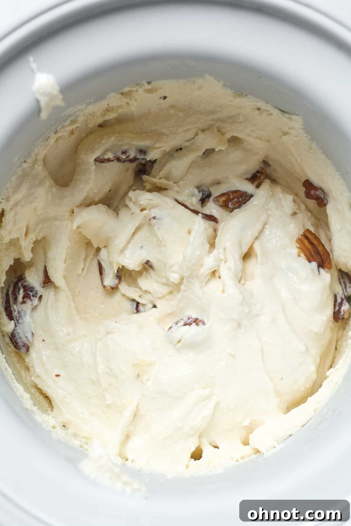 Toasted pecans being folded into churned ice cream.