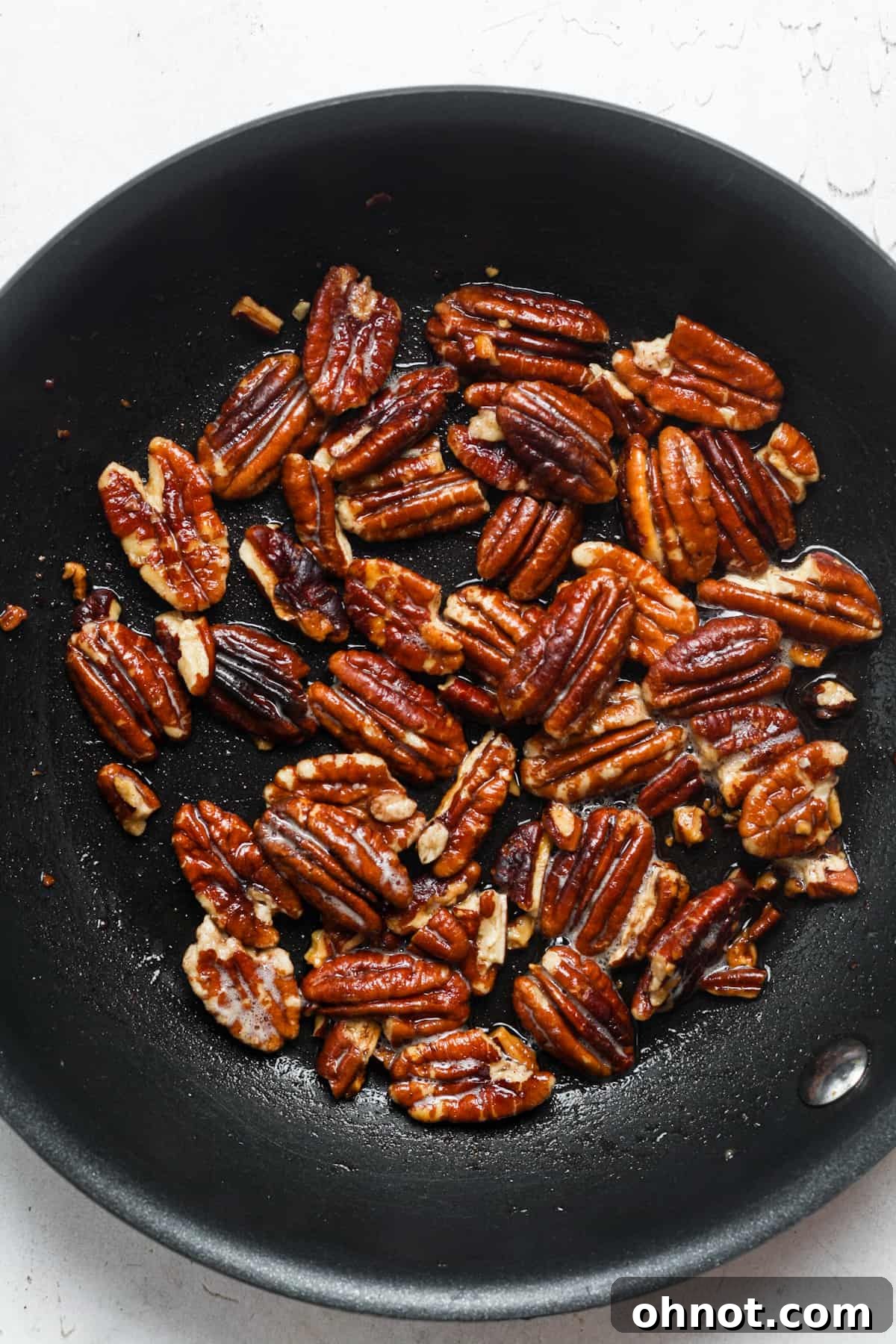 Buttered pecans cooling on a paper towel after toasting.