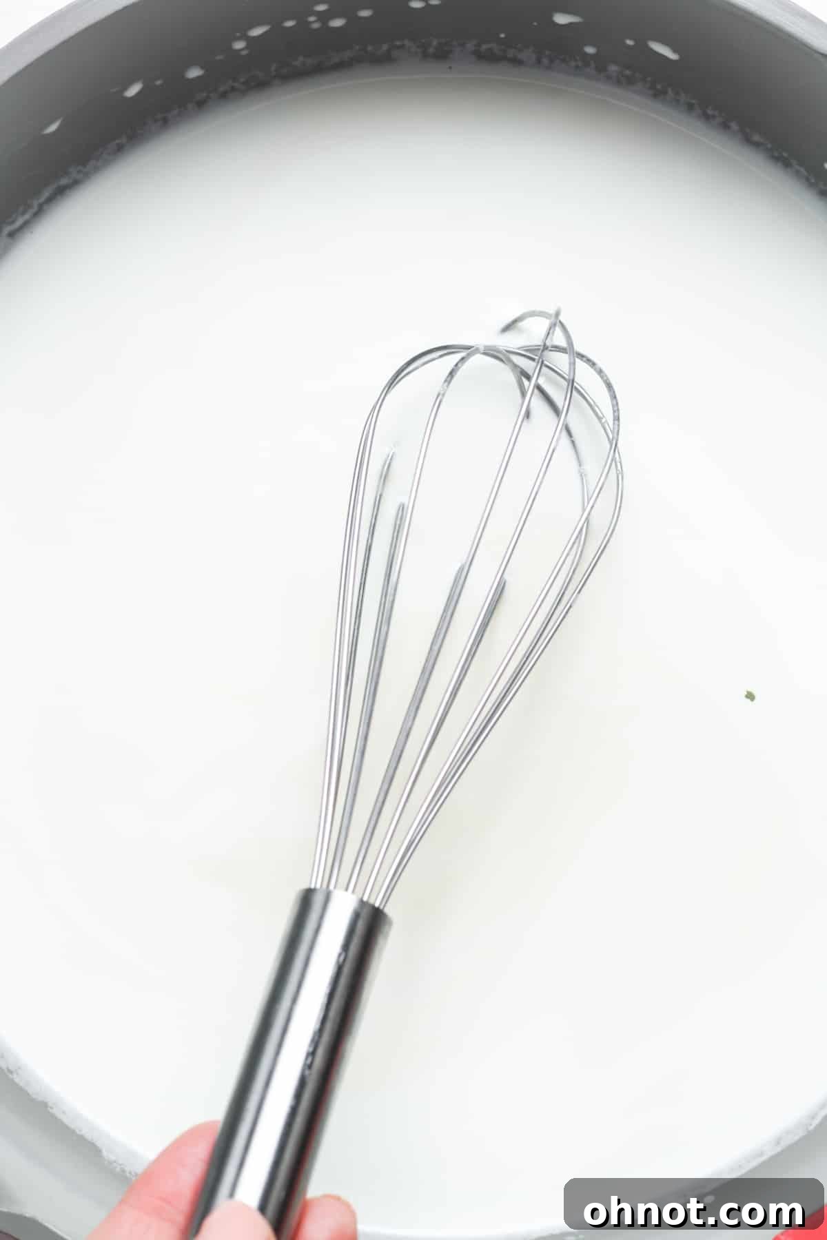 Whisk stirring milk and sugar in a skillet.