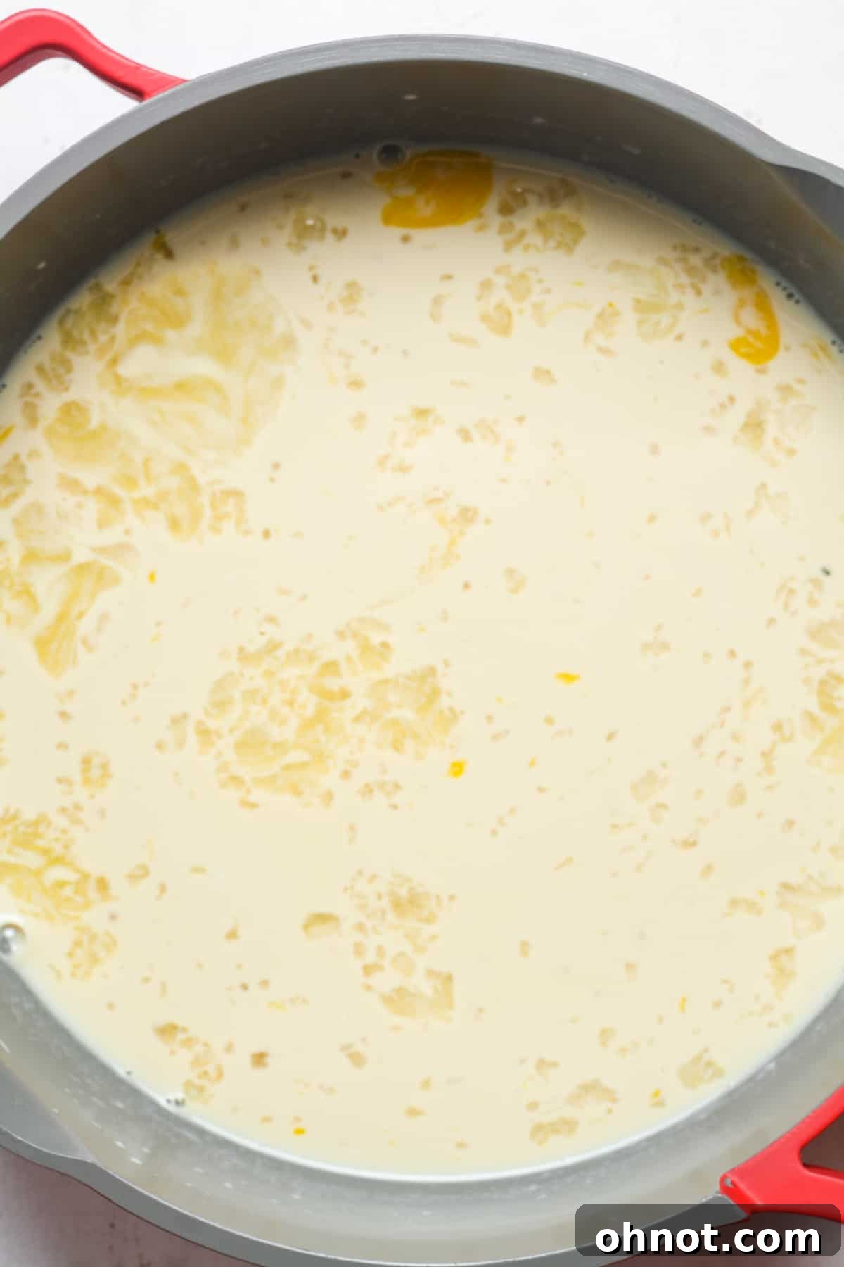 Warm cream mixture being slowly added to whisked eggs.