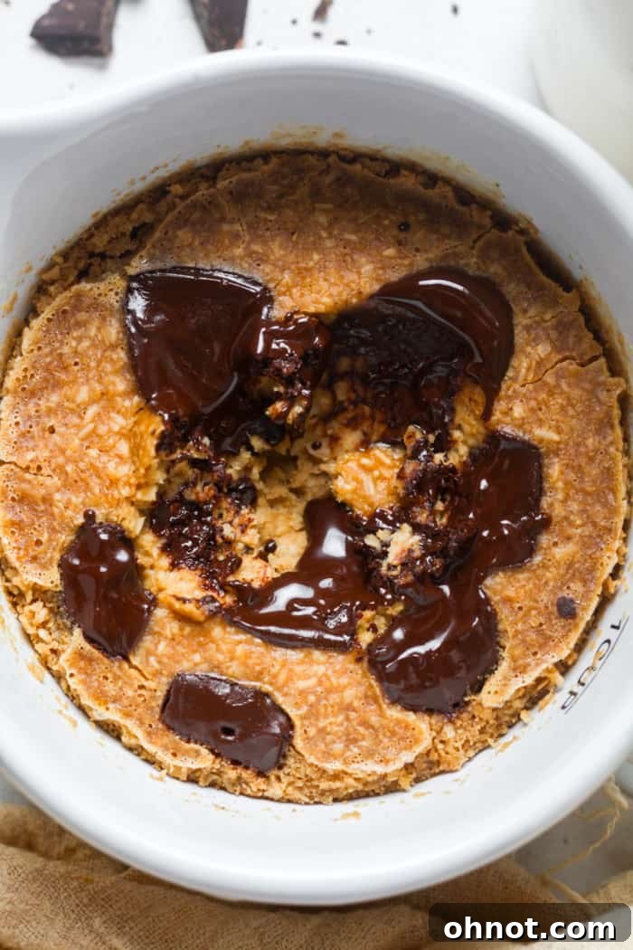 Personal cake-like baked oats in a mug, topped with chocolate.