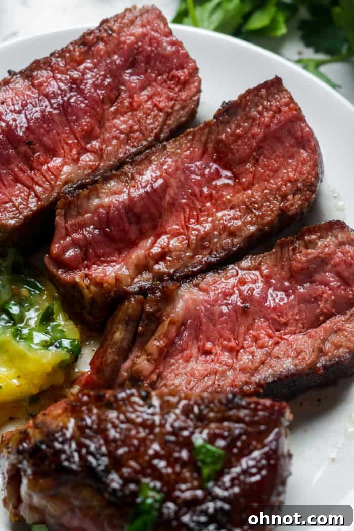 Perfectly cooked medium-rare Denver steak, sliced, on a plate.