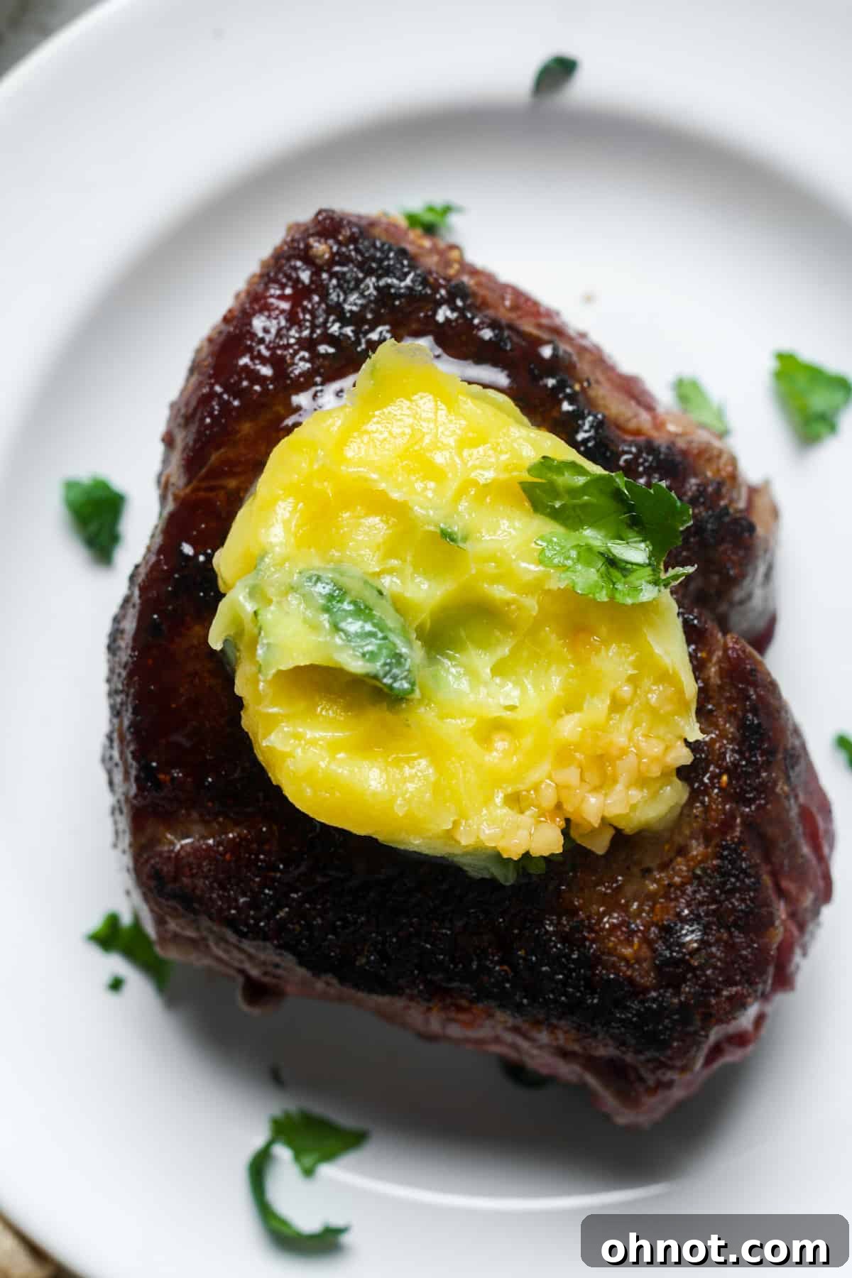 Cooked Denver steak topped with melting herb butter.