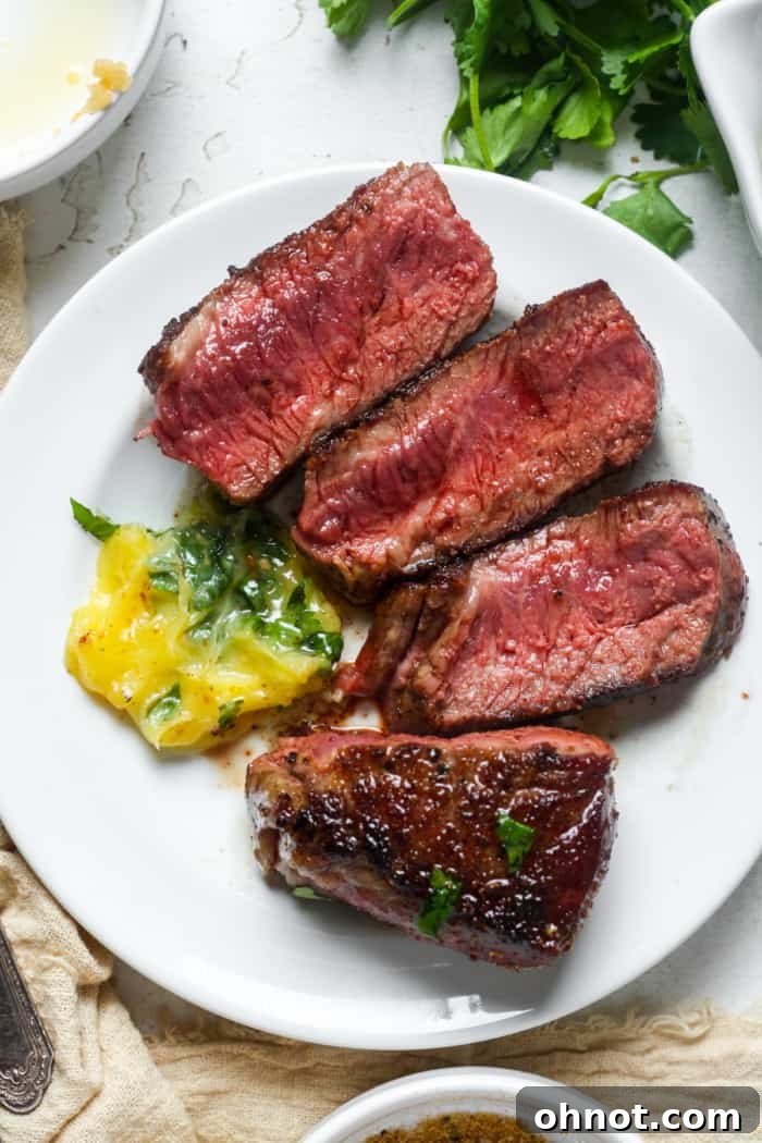 Sliced Denver steak served on a plate with herb butter and garnishes.
