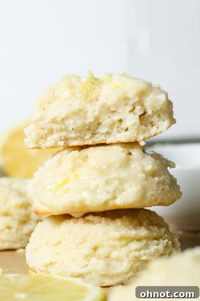 Stack of glazed lemon ricotta cookies with fresh lemon slices.