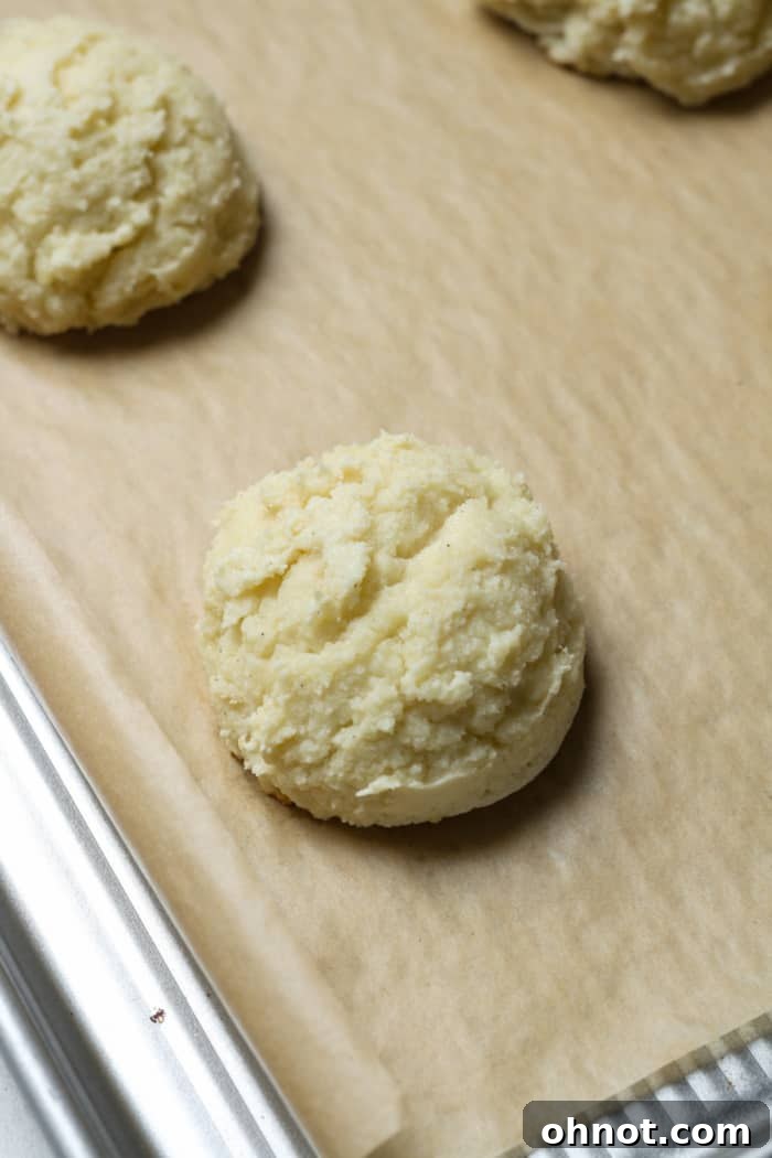 Freshly baked lemon ricotta cookies cooling on a baking sheet.