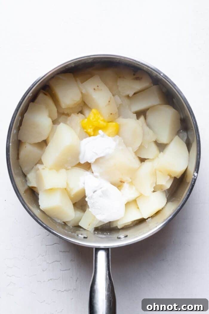 Drained potatoes with coconut milk and ghee added in the pot