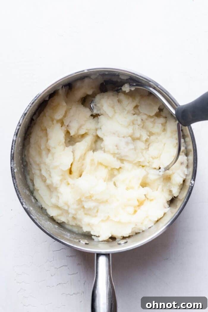 Potato masher in a pot with partially mashed potatoes