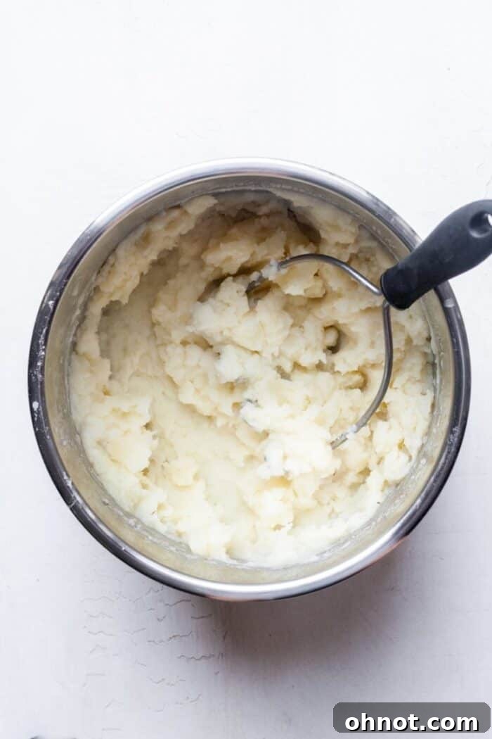 Potato masher actively mashing potatoes in the Instant Pot