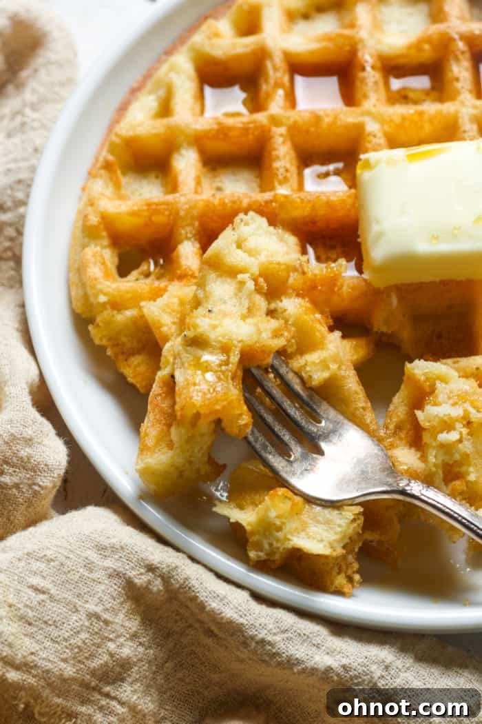 A fork holding a piece of a golden gluten-free waffle.