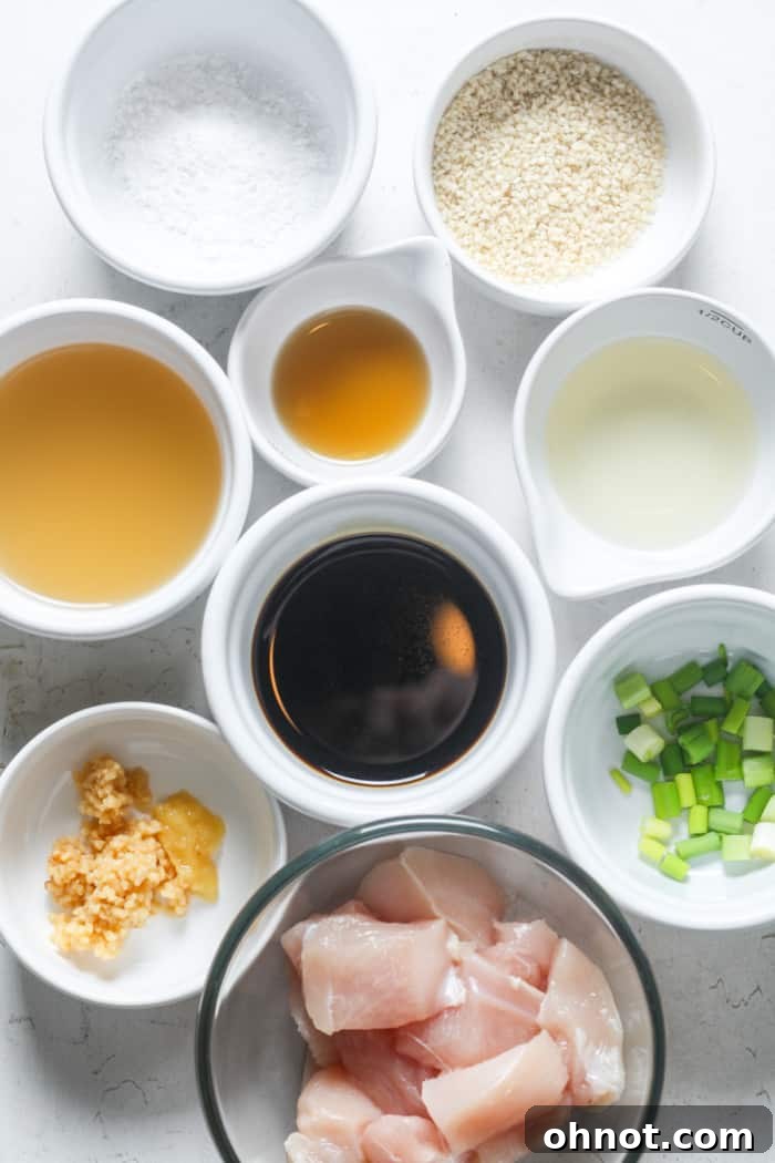 A selection of fresh ingredients laid out for Chinese garlic chicken, including chicken, garlic, ginger, oils, and sauces.