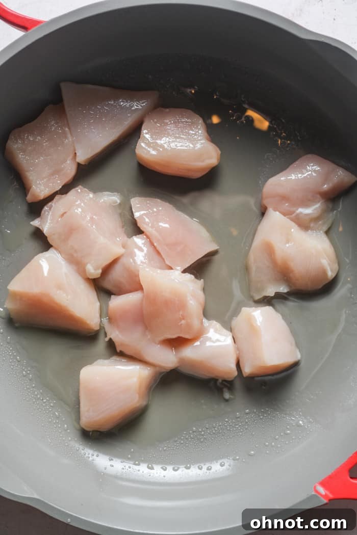 Raw cubed chicken in a hot skillet with olive oil.