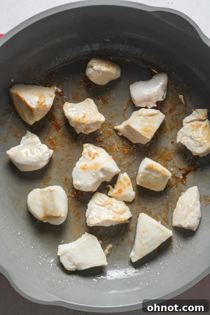 Golden-brown cubed chicken in a pan, ready for sauce.