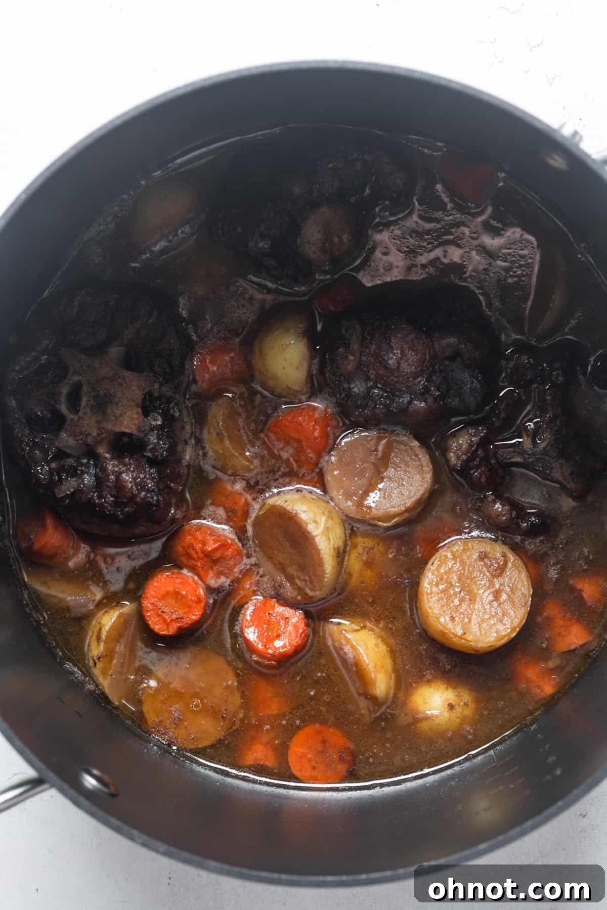 Oxtail stew with carrots and potatoes in a pot.