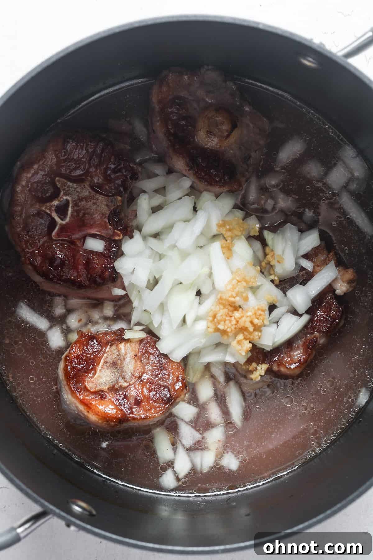 Beef with sautéed onions and garlic in a pot.
