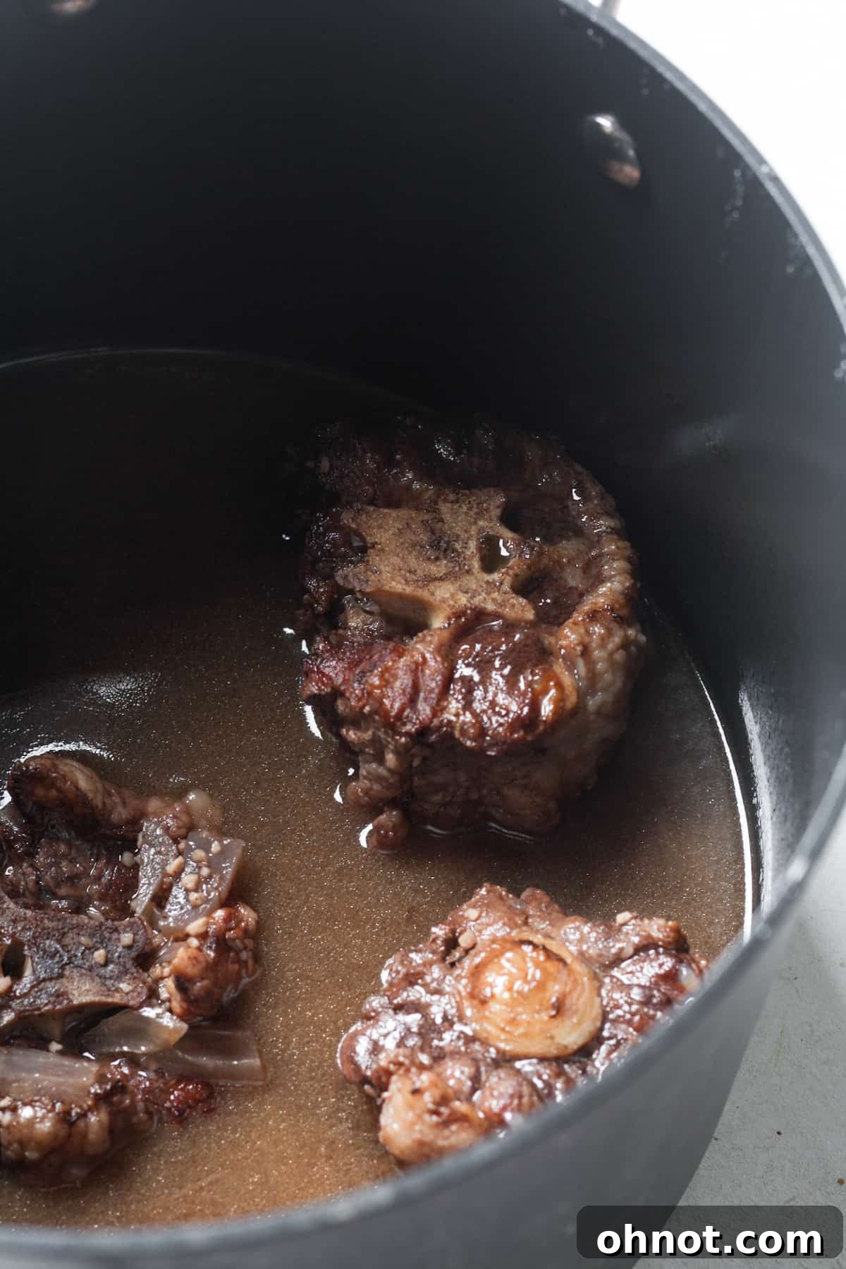 Meat simmering in a Dutch oven with liquids.