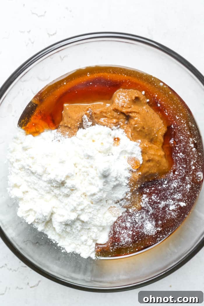 Close-up of peanut butter and coconut flour in a mixing bowl.