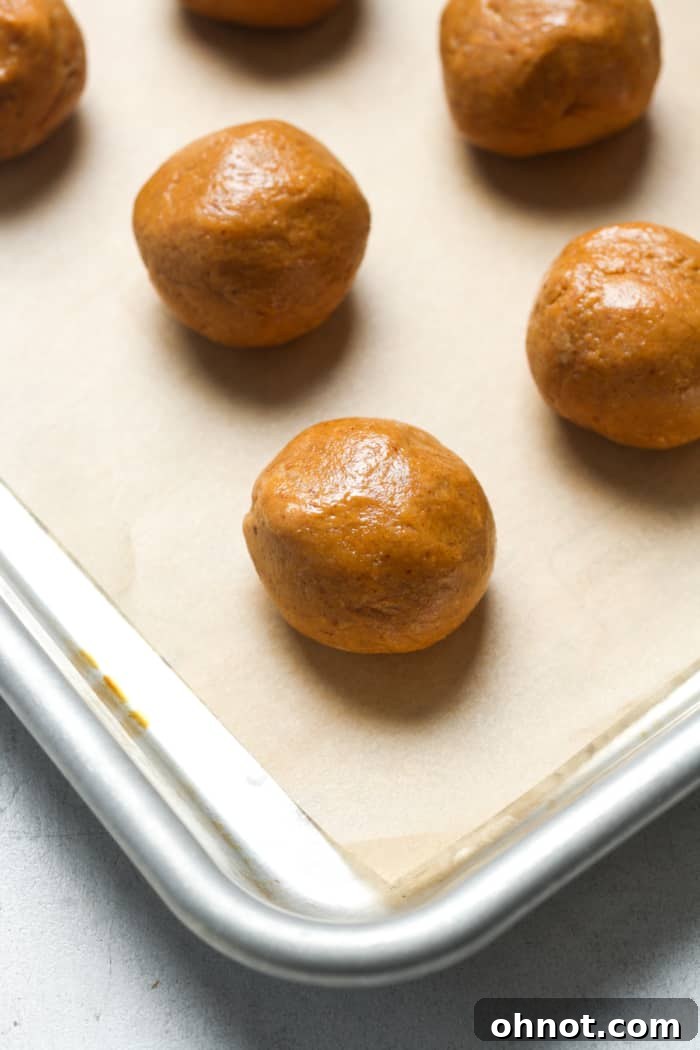 Rolled peanut butter dough balls on a parchment-lined baking pan.