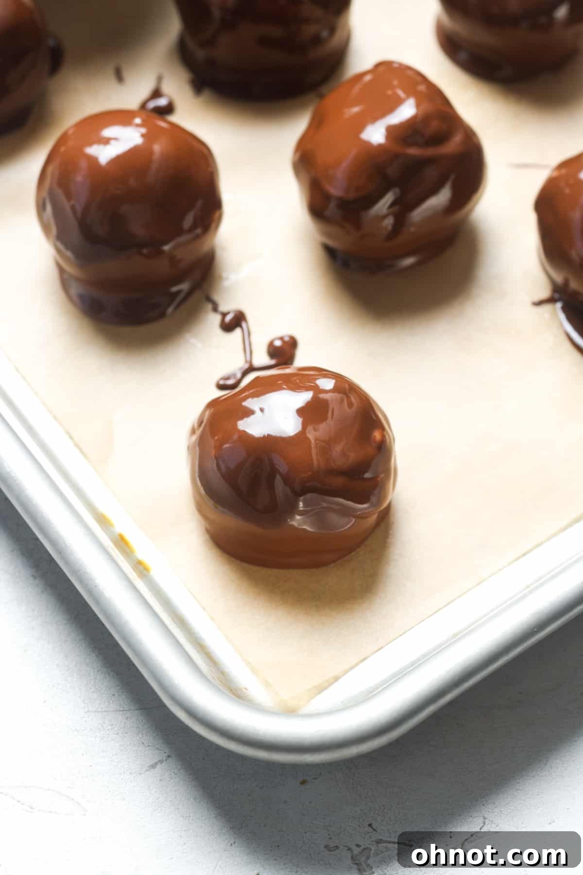 Chocolate-coated peanut butter balls on a baking sheet.