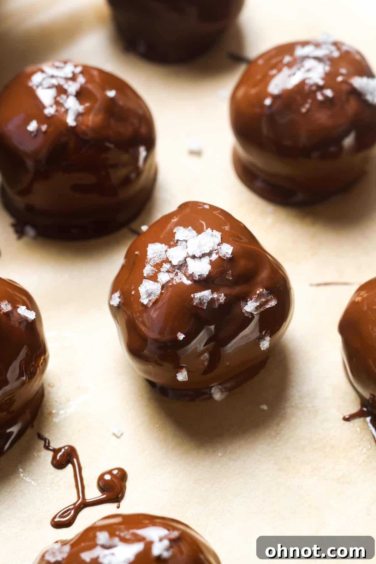 Chocolate-coated balls garnished with sea salt on a baking sheet.