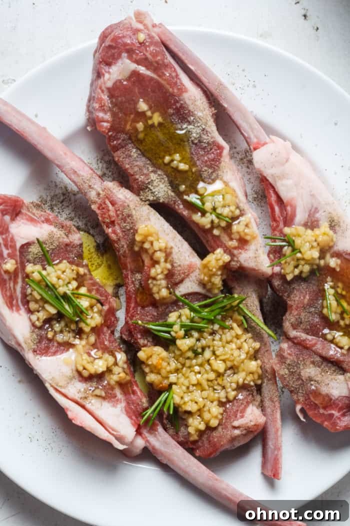 Lamb chops covered in the garlic and rosemary marinade, resting in a bowl.