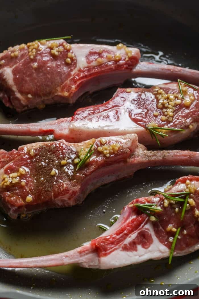 Pieces of marinated lamb lollipops sizzling in a hot skillet with olive oil.