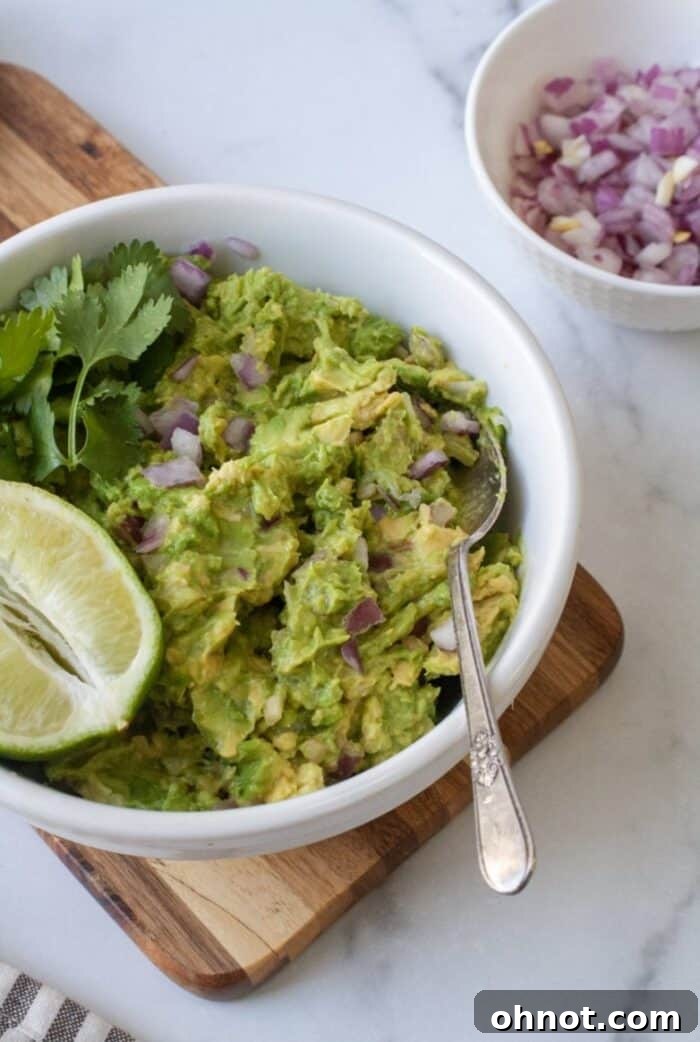 Bowl of guacamole with cilantro, onions and lime