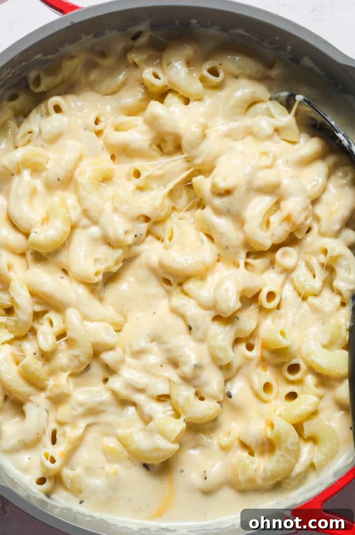 Cooked macaroni pasta generously coated in a creamy cheese sauce, still in the skillet.