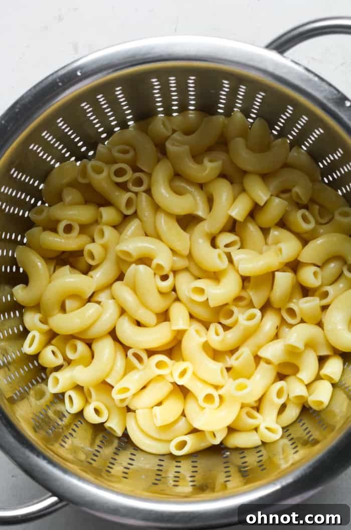 Cooked macaroni pasta in a colander, ready to be drained and mixed.