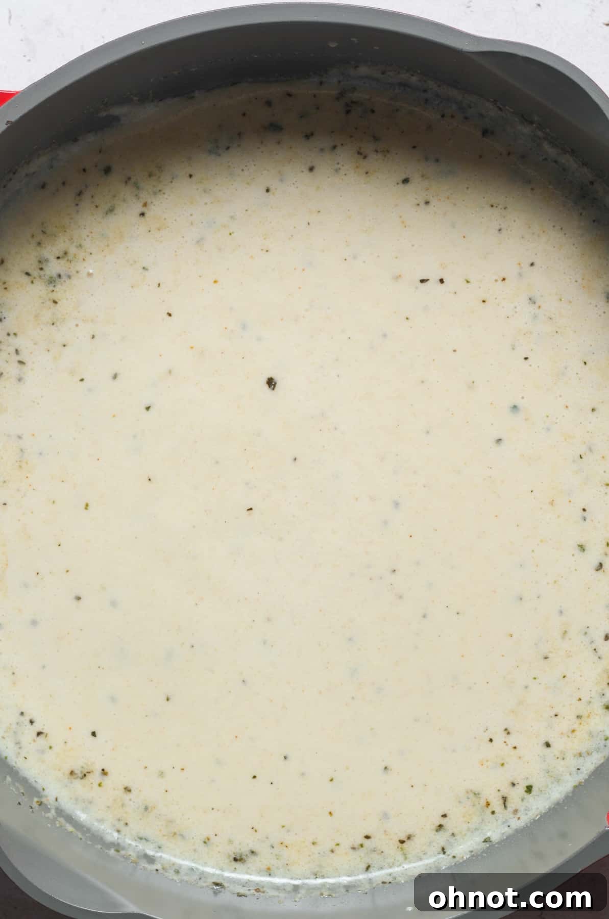 The mac and cheese sauce, now a light beige, continues to thicken in the pan, indicating it's nearly ready for cheese.