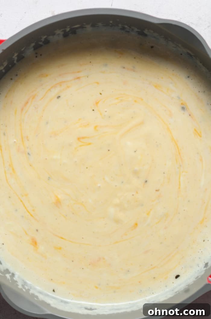 A rich, creamy, and golden cheese sauce in a skillet, perfectly melted and ready for pasta.