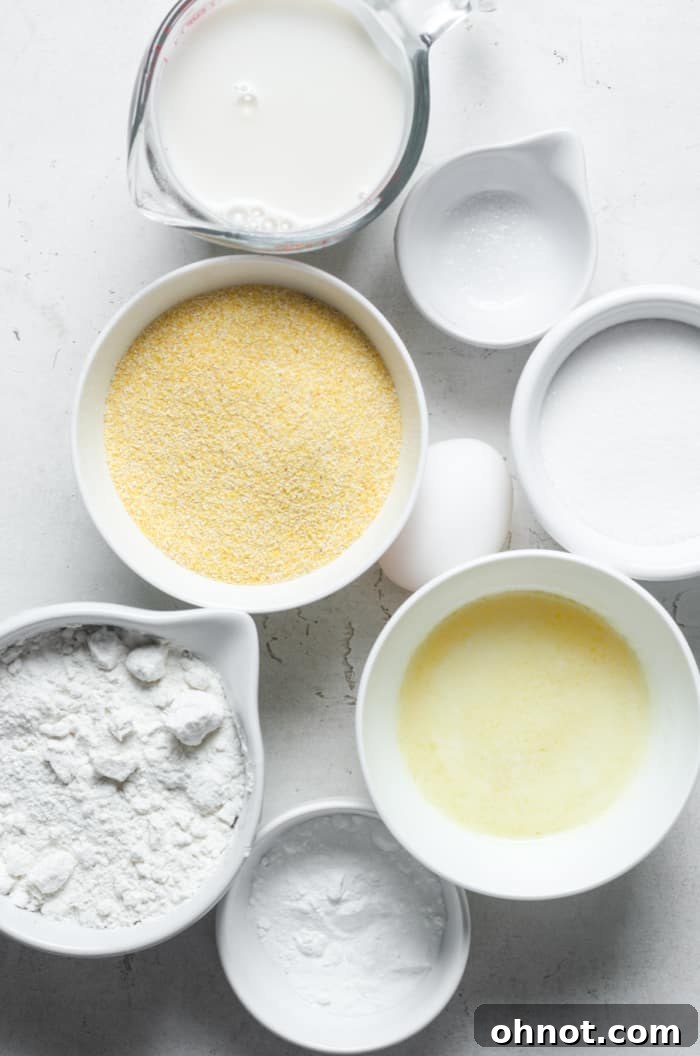 A vibrant selection of fresh ingredients neatly arranged on a countertop, including gluten-free flour, yellow cornmeal, butter, buttermilk, eggs, and sugar, all ready for making delicious cornbread.