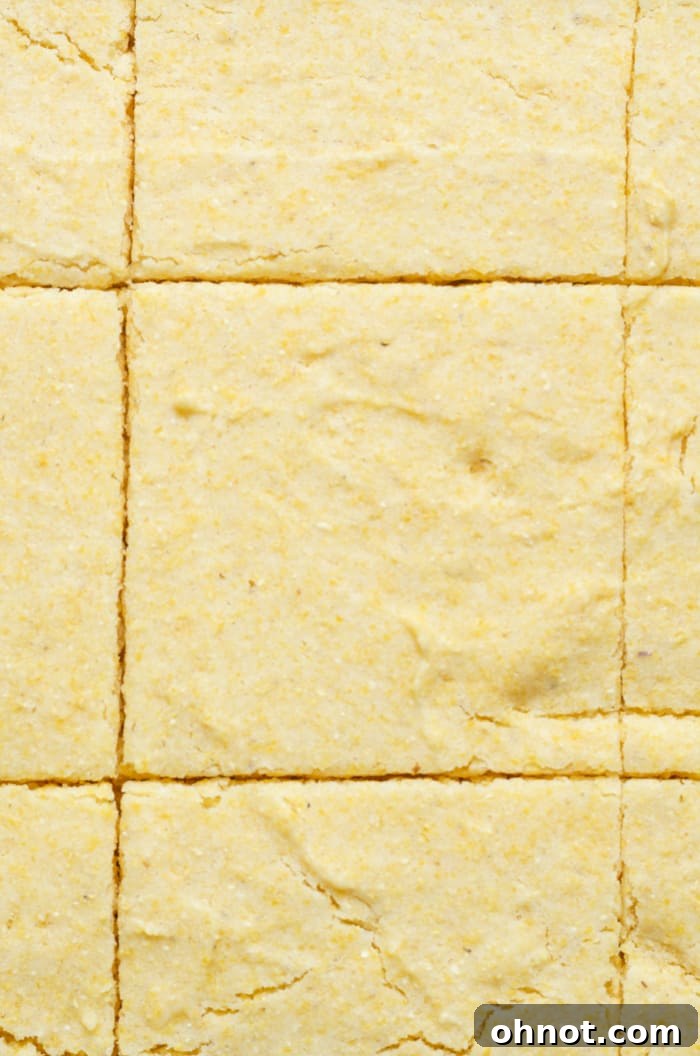 A freshly baked gluten-free cornbread, sliced into neat squares, sitting in a baking pan, ready to be served.