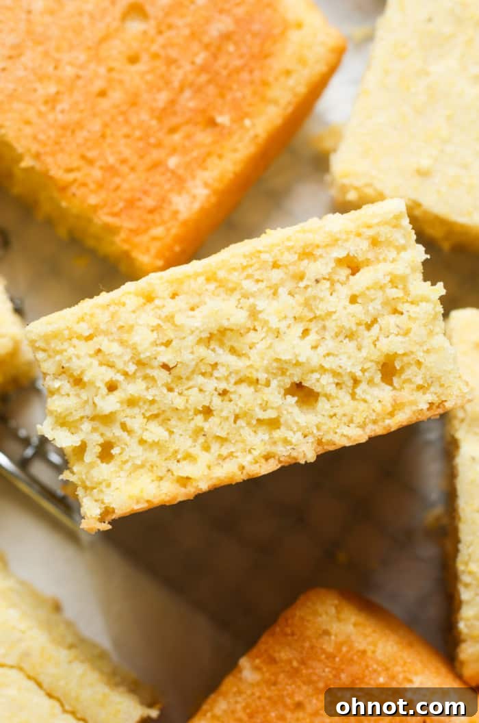 A close-up of a moist, yellow slice of gluten-free cornbread on a plate, highlighting its tender crumb and inviting texture.