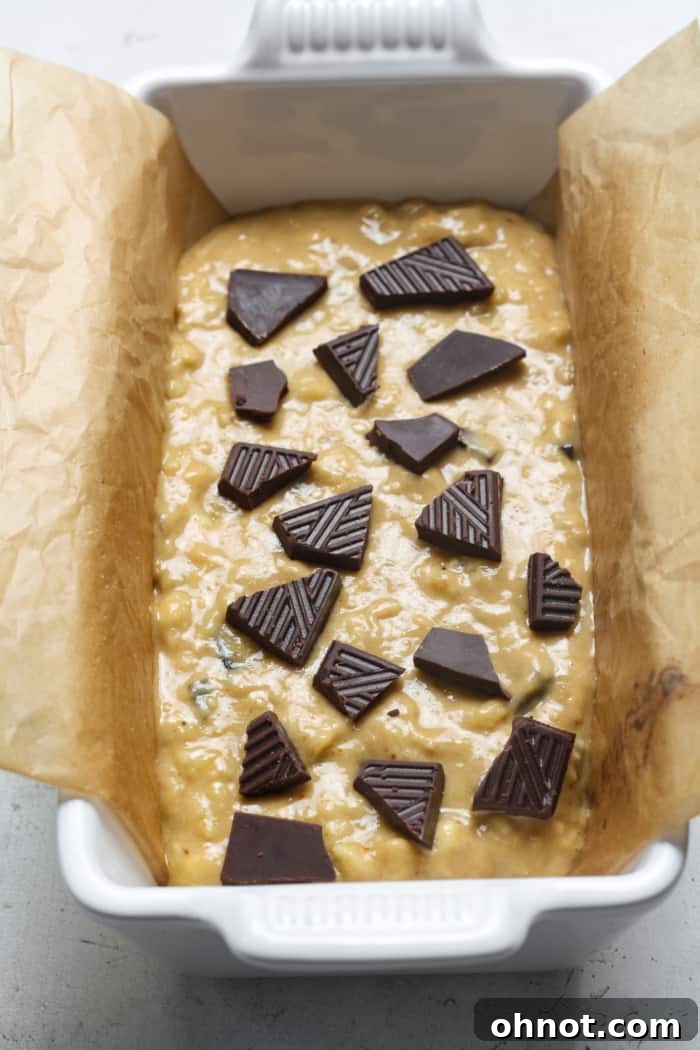 Bread pan filled with banana bread batter, topped with chocolate.