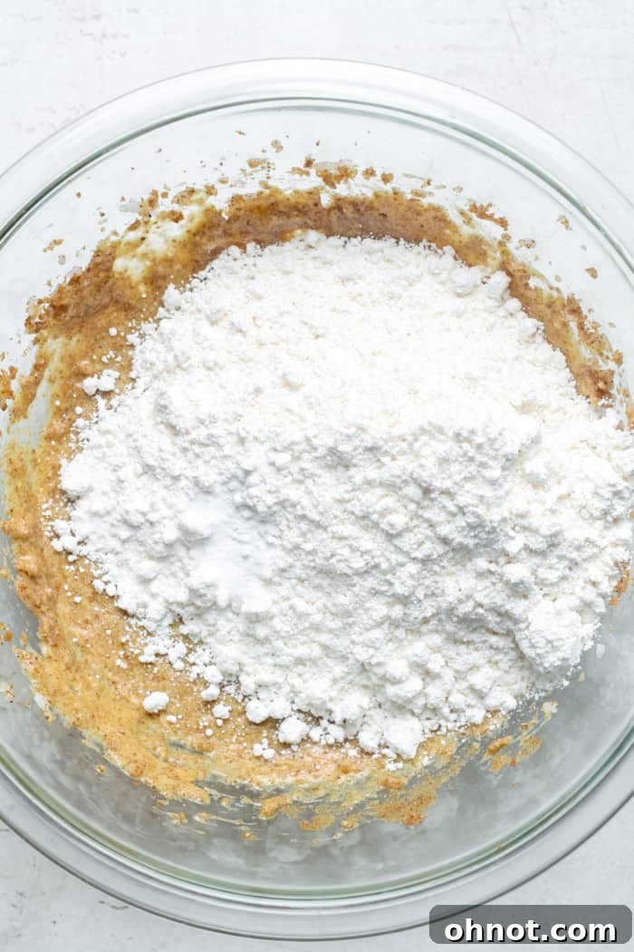 Paleo flours being added to the wet ingredients in a bowl.