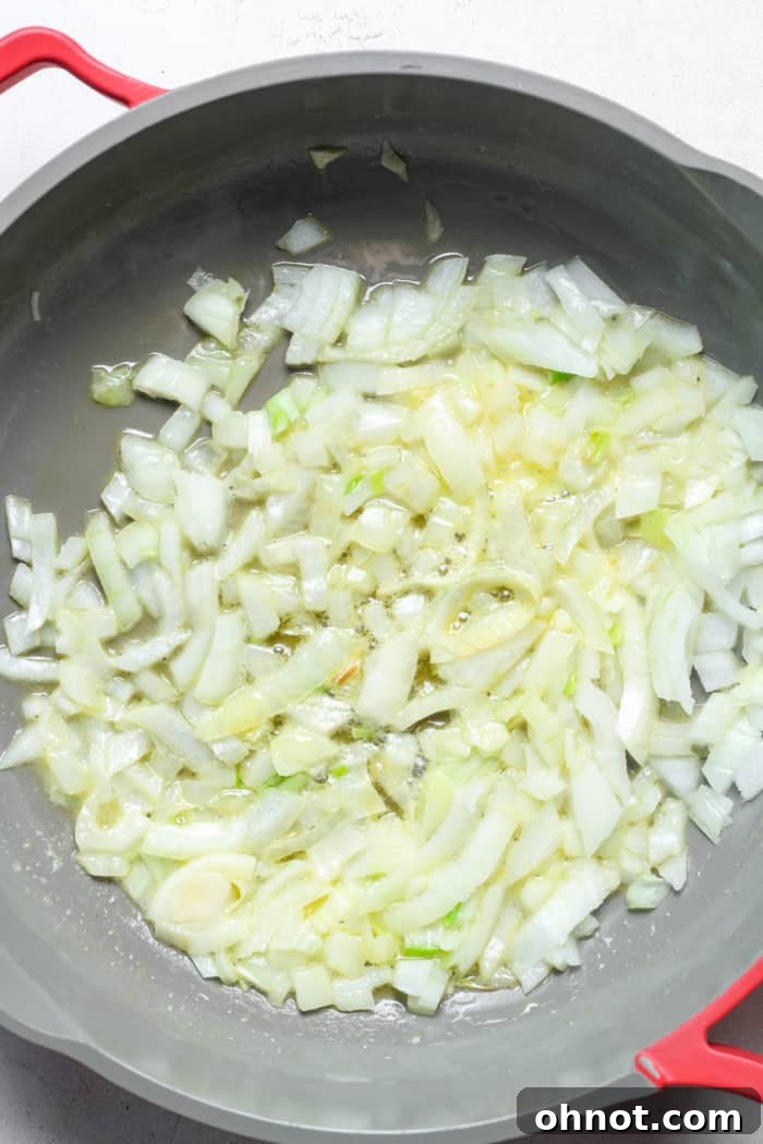 Chopped yellow onions beginning to sauté in a skillet with melted butter.