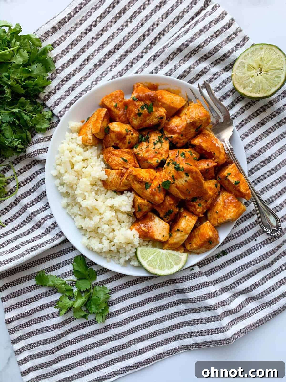 Whole30 Chicken Tikka Masala served over cauliflower rice in a bowl, garnished with fresh herbs.