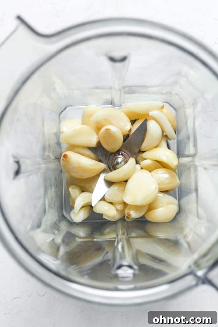 Peeled garlic cloves placed in a blender, ready to be minced.