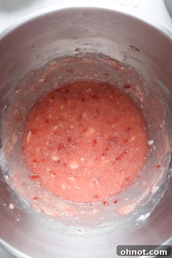 Pink strawberry mixture in a mixing bowl.
