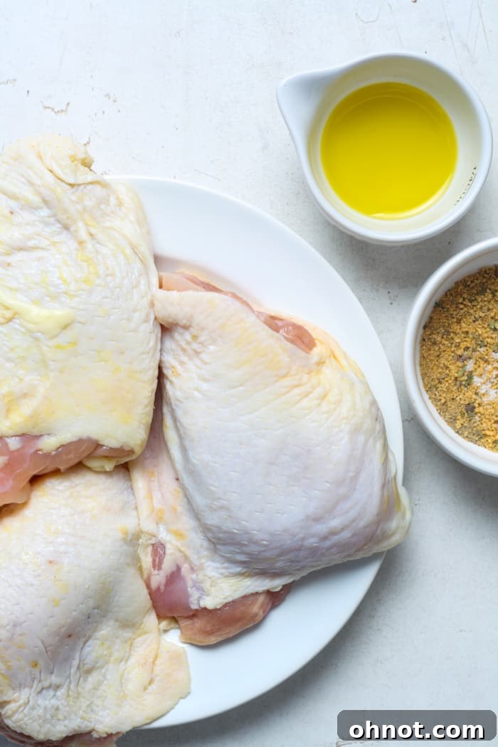 A selection of raw ingredients for baked chicken thighs, including chicken, olive oil, and various spices.