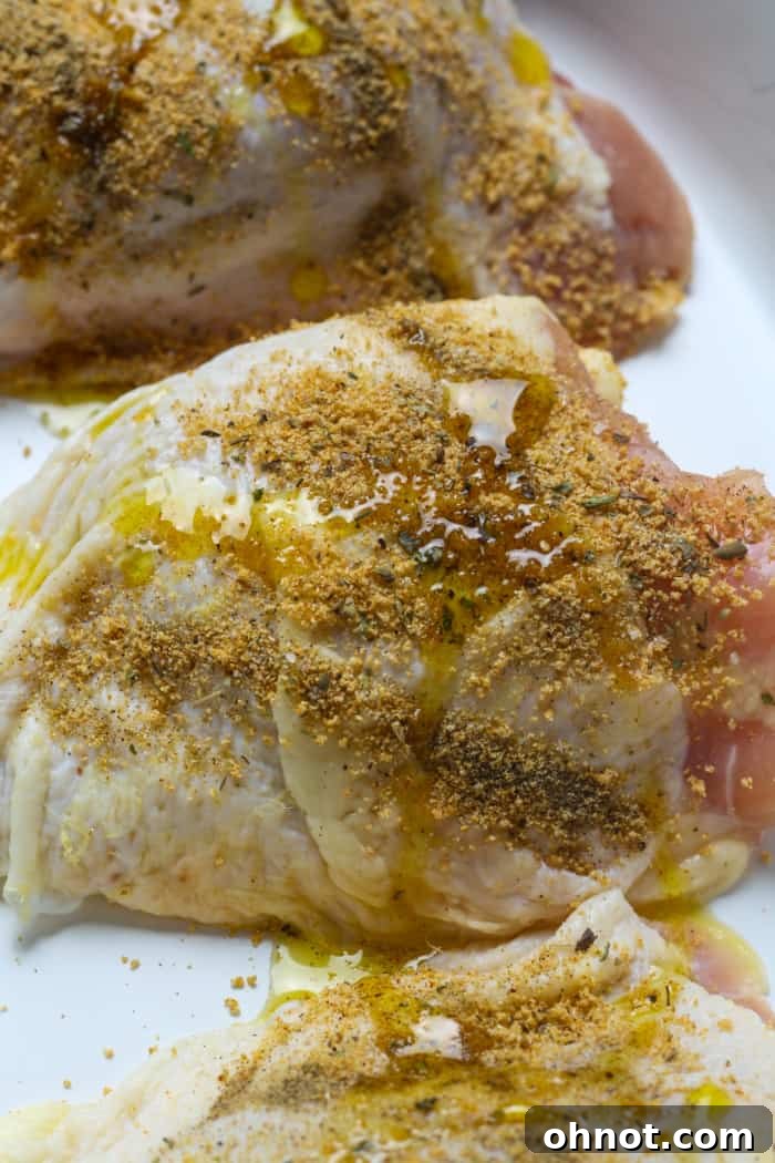 Seasoned chicken thighs neatly arranged in a baking pan, ready for the oven.