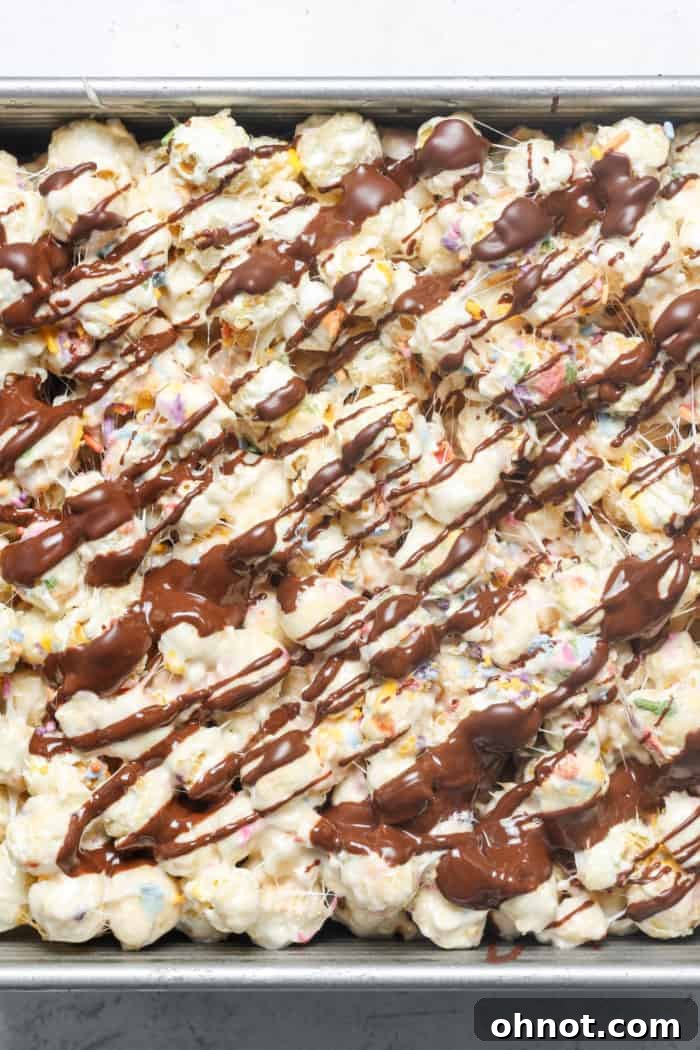 Melted chocolate drizzled artfully over the popcorn bars, ready for sprinkles.