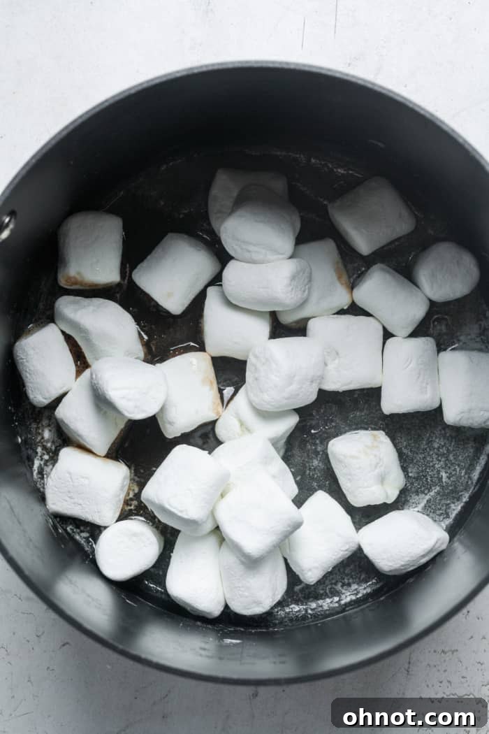 Marshmallows added to melted butter in a pan, beginning to soften.