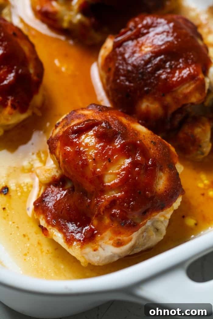 Partially baked chicken being brushed with more BBQ sauce.