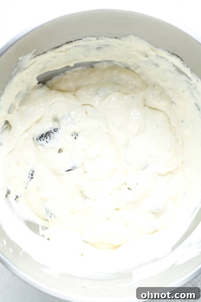 Cheesecake batter with generous pieces of crushed Oreos folded in, ready for baking.