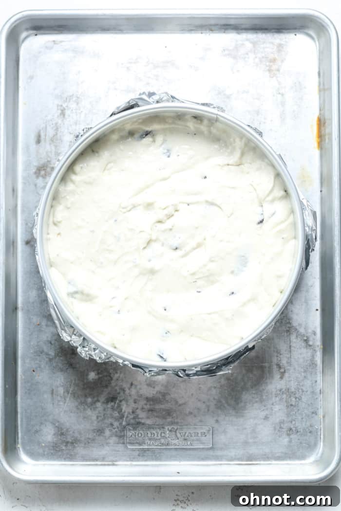 Unbaked Oreo cheesecake filling poured evenly over the crust in a springform pan.